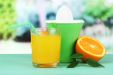 Citrus press, glass of juice and ripe orange