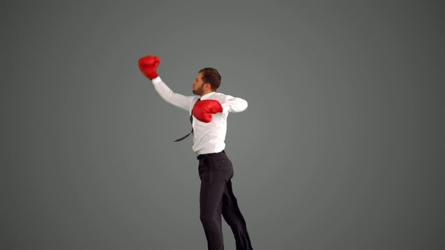 Businessman in boxing gloves leaping and punching