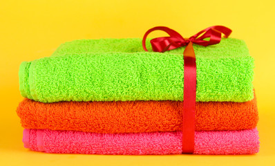 Fototapeta na wymiar Towels tied with ribbon on yellow background