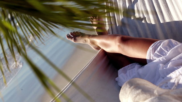 Woman relaxing in a hammock under a palm tree