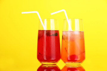 Two cherry cocktails with ice on yellow background.Keyword