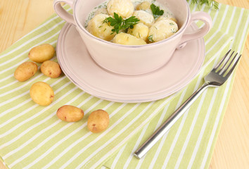 Tender young potatoes with sour cream and herbs in pan