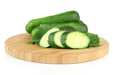 Tasty green cucumbers on wooden cutting board, isolated on