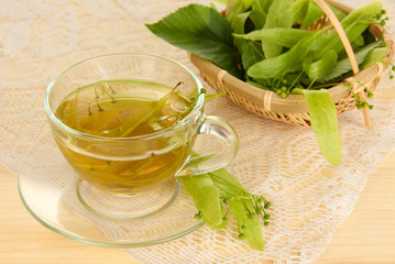 Glass cup of tea with linden on wooden table close-up