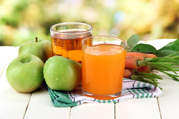 Glasses of juice, apples and carrots