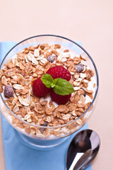 yogurt with muesli and raspberries in small glass 