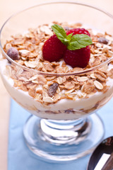 yogurt with muesli and raspberries in small glass 