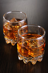 Brandy glasses with ice on wooden background