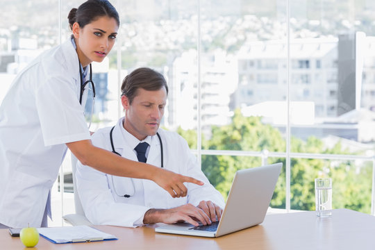 Doctor pointing at the laptop of a colleague