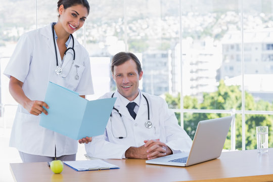 Pretty doctor showing a folder to a colleague