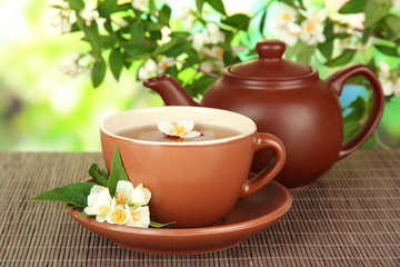 Cup of tea with jasmine, on bamboo mat, on bright background