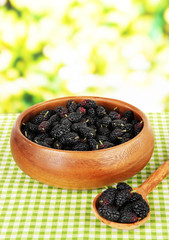 Fototapeta na wymiar Ripe mulberries in bowl on table on bright background