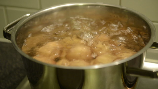 Small potatoes boiling in a large saucepan on the stove top