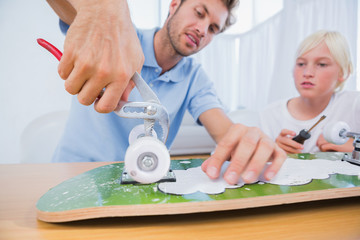 Father repairing a skateboard with his son