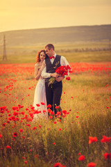 The bride and groom in a poppy field