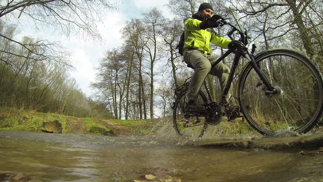 Man rides a bicycle through a creek