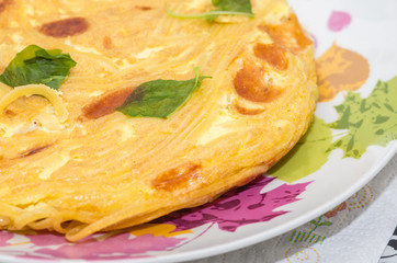 Close-up of a frittata of pasta with basil leaves