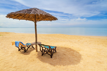 Tropical beach scenery with parasol and deck chairs in Thailand