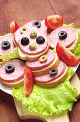 Sandwiches with sausage, lettuce, tomato and olives