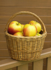 Many red and yellow apples in small brown wicker basket