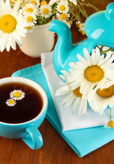 Beautiful bouquet chamomiles in teapot on wooden table close-up