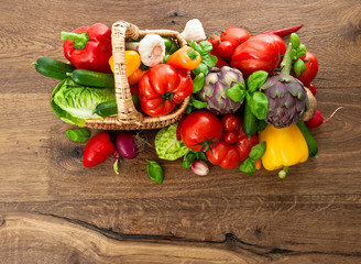 fresh vegetables and herbs in basket on wooden background