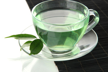 Transparent cup of green tea on bamboo mat, isolated on white