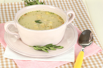 Nourishing soup in pink pan on wooden table close-up