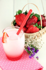 Delicious strawberry yogurt in glass on wooden table close-up