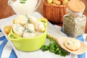 Tender young potatoes with sour cream and herbs in pan