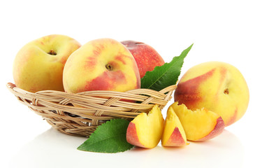 Ripe sweet peaches with leaves in basket, isolated on white