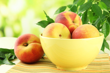 Ripe sweet peaches on table in bowl, outdoors