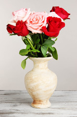 Fototapeta premium Beautiful bouquet of roses in vase on table on gray background
