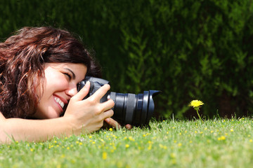 Beautiful woman taking a photography of a flower on the grass