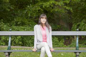 Obraz premium young woman seated on a bench in the park