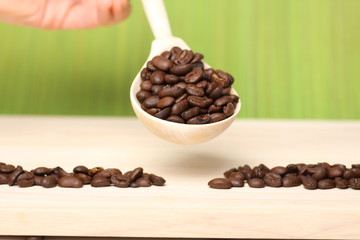 coffee beans on wooden surface with wooden spoon