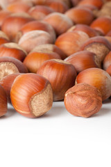 Unbroken hazelnuts on white surface