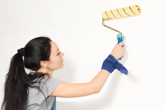 Woman painting a wall with a roller