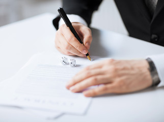Naklejka premium man hands with gambling dices signing contract
