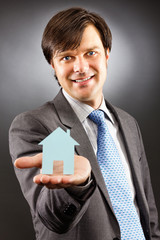 Young business man holding a model of a house on his palm