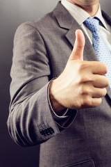 Closeup of a businessman's hand showing thumb up