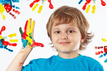 Young boy with painted hands on a background of hand prints