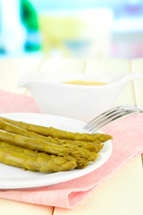 Asparagus on plate, on wooden table on bright background