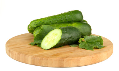 Tasty green cucumbers on wooden cutting board, isolated on