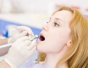 young woman with open mouth during drilling treatment 