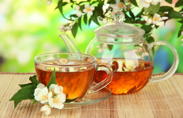 Cup of tea with jasmine, on bamboo mat, on bright background