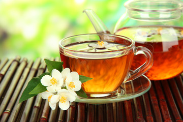 Cup of tea with jasmine, on bamboo mat, close-up