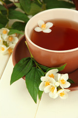 Obraz na płótnie Canvas Cup of tea with jasmine, on wooden table, close-up
