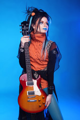 Rock girl posing with electric guitar isolated on blue backgroun