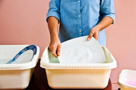 Washing dishes by hand to save water.
